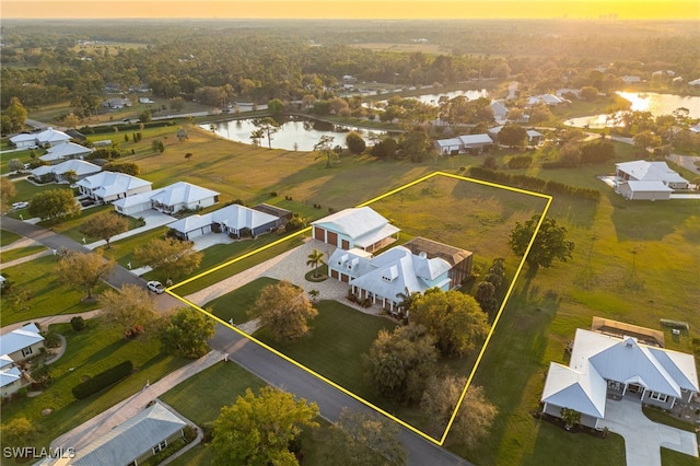 aerial view at dusk featuring a water view and a residential view