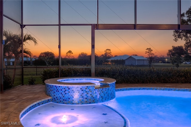 view of pool featuring glass enclosure, a patio area, and a pool with connected hot tub