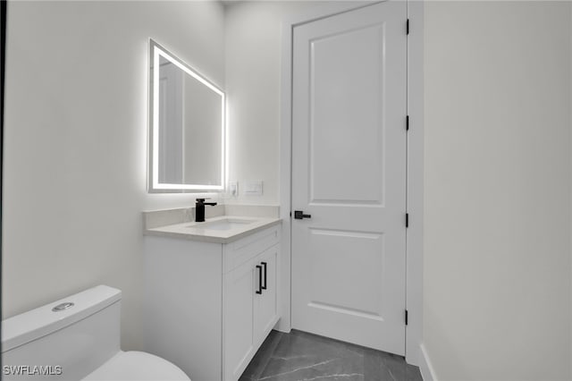 bathroom with marble finish floor, vanity, and toilet