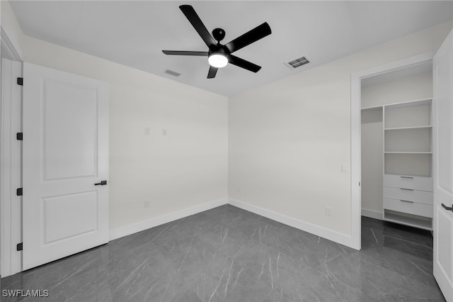 unfurnished bedroom with a walk in closet, marble finish floor, visible vents, and baseboards