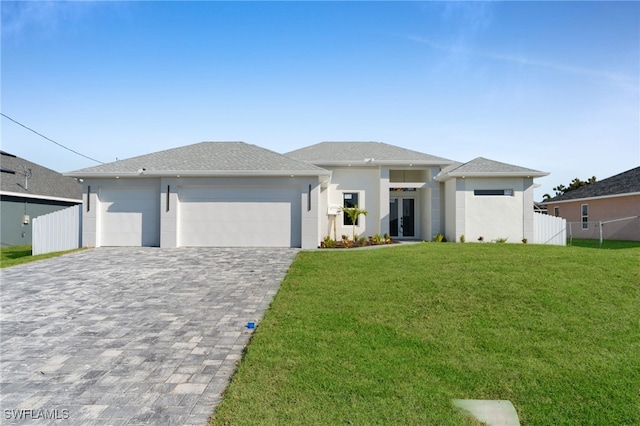 prairie-style home with an attached garage, fence, decorative driveway, french doors, and a front yard