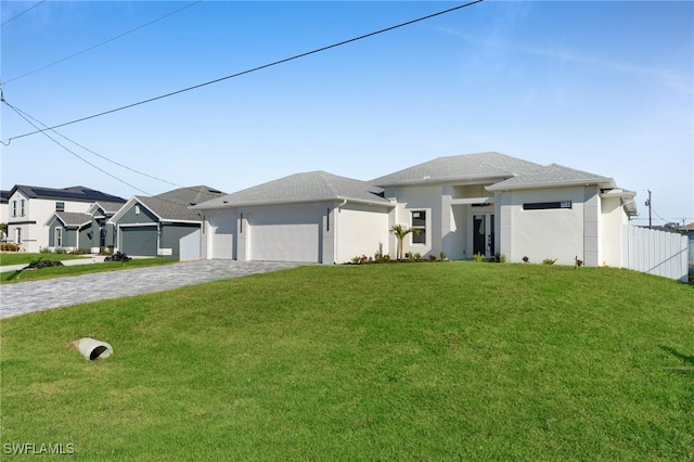 view of front of house featuring a front yard, decorative driveway, fence, and an attached garage