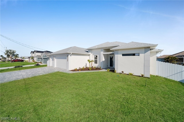 prairie-style home with decorative driveway, a front yard, fence, and stucco siding