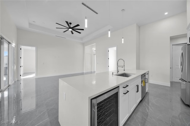 kitchen featuring a raised ceiling, wine cooler, appliances with stainless steel finishes, pendant lighting, and a sink