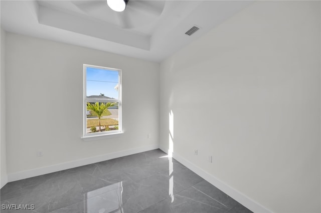 unfurnished room with a ceiling fan, a raised ceiling, visible vents, and baseboards