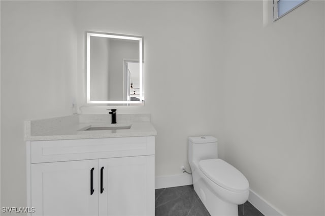 bathroom featuring toilet, tile patterned floors, baseboards, and vanity