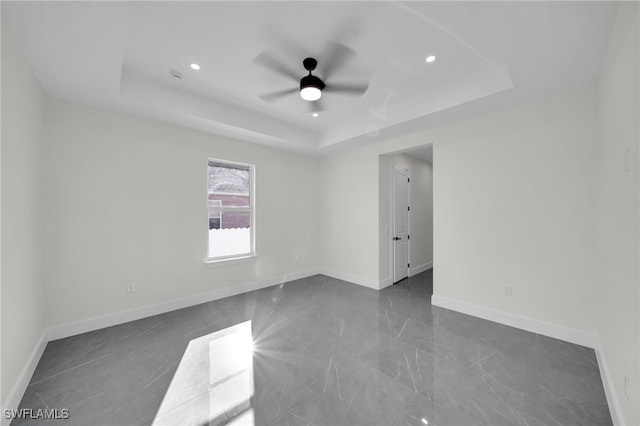 spare room with a ceiling fan, recessed lighting, a raised ceiling, and baseboards