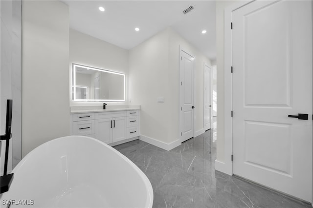 full bathroom featuring baseboards, marble finish floor, vanity, a freestanding tub, and recessed lighting