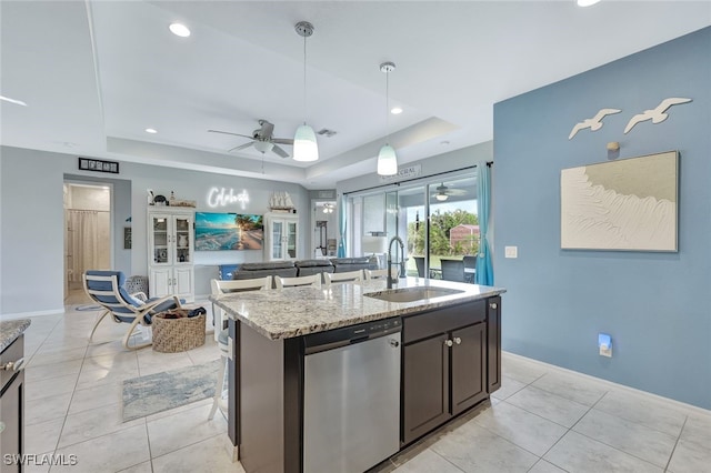 kitchen with a raised ceiling, a sink, open floor plan, and stainless steel dishwasher