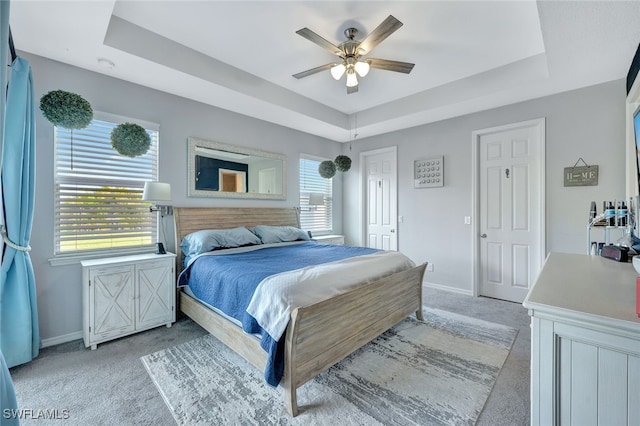 bedroom featuring baseboards, a tray ceiling, and light colored carpet