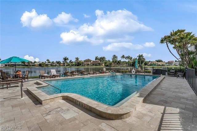 community pool featuring a water view, a patio, and fence