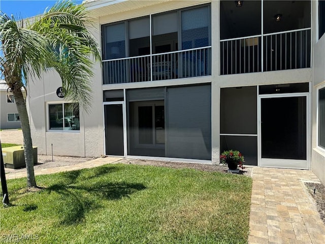 rear view of property featuring a lawn and stucco siding