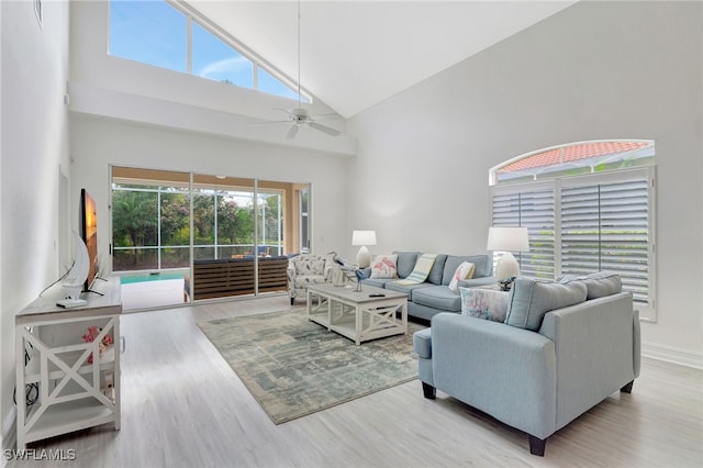 living room with baseboards, wood finished floors, a sunroom, high vaulted ceiling, and a ceiling fan