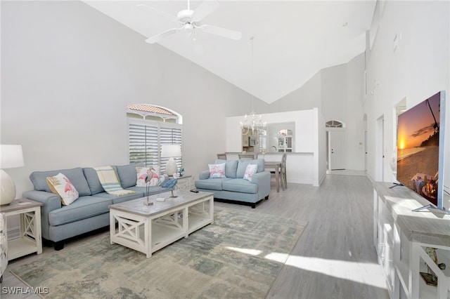 living room featuring ceiling fan with notable chandelier, wood finished floors, and high vaulted ceiling