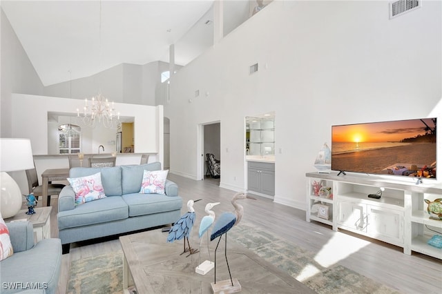 living area with visible vents, wood finished floors, baseboards, and a chandelier