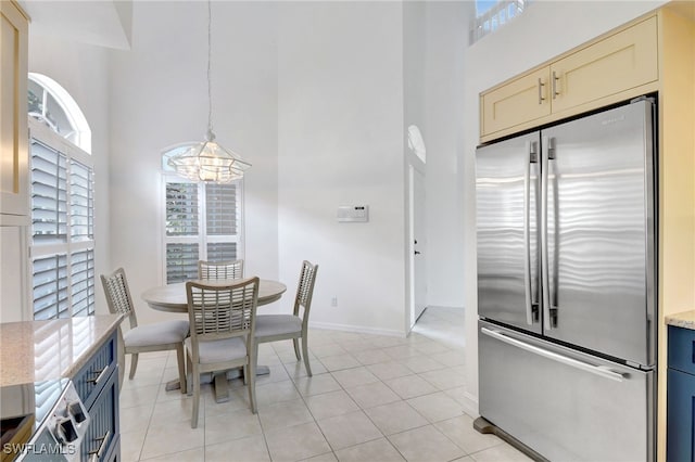 dining area featuring light tile patterned floors, a healthy amount of sunlight, a high ceiling, and baseboards