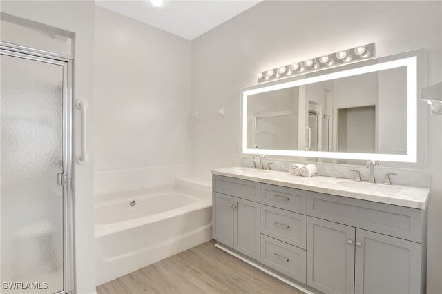 bathroom with a sink, double vanity, wood finished floors, and a shower stall