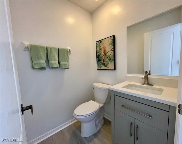 bathroom featuring toilet, vanity, baseboards, and wood finished floors