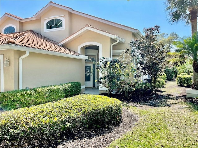 view of front of property with stucco siding, a tiled roof, and a garage