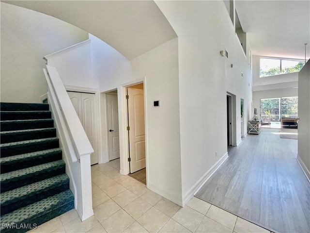 staircase with baseboards, a towering ceiling, and tile patterned flooring