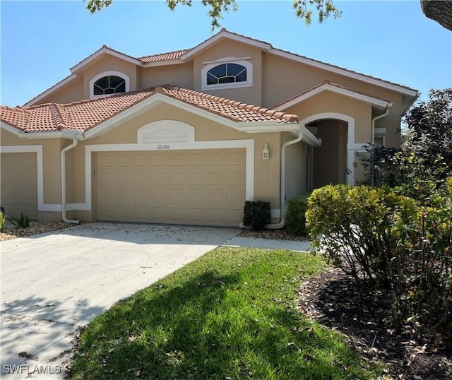 mediterranean / spanish-style house featuring stucco siding, a tiled roof, concrete driveway, and a garage