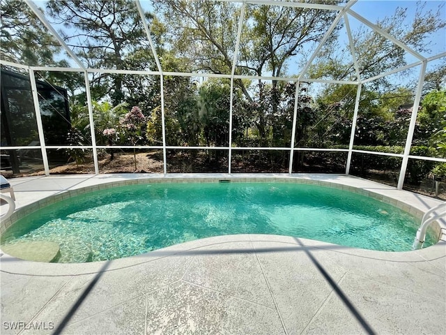 outdoor pool featuring glass enclosure and a patio