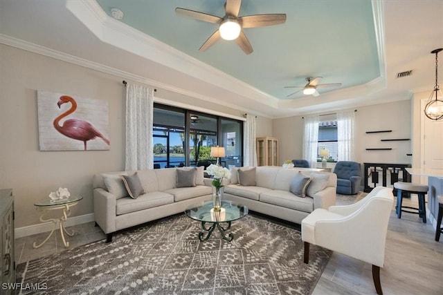 living area with visible vents, a tray ceiling, and crown molding