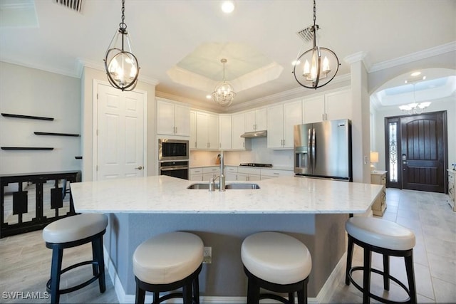 kitchen featuring white cabinets, a raised ceiling, stainless steel appliances, crown molding, and a sink