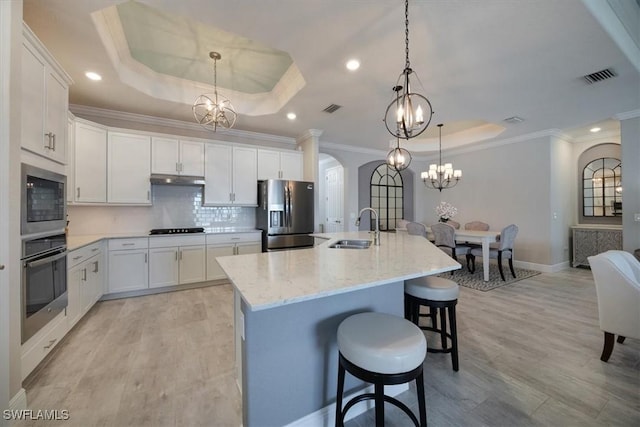 kitchen featuring appliances with stainless steel finishes, a tray ceiling, a notable chandelier, and a sink