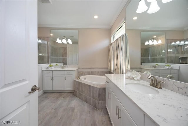 bathroom with two vanities, wood finished floors, a sink, crown molding, and a bath