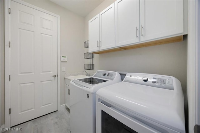 laundry area featuring cabinet space, washer and clothes dryer, and a sink