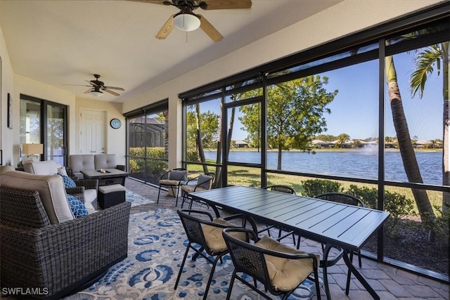 sunroom featuring ceiling fan and a water view