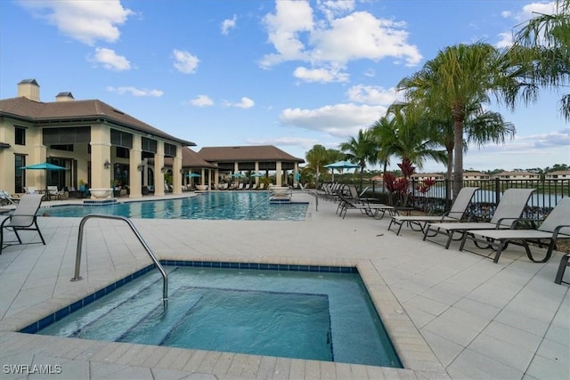 pool featuring a patio area, fence, and a hot tub