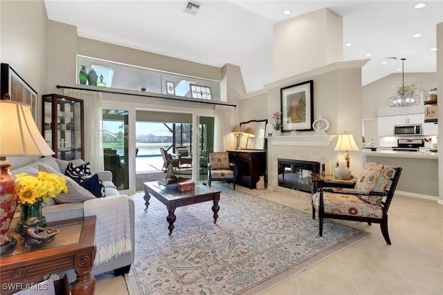 living room featuring light tile patterned flooring, a fireplace with flush hearth, a towering ceiling, visible vents, and an inviting chandelier