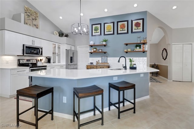 kitchen with a sink, a kitchen breakfast bar, appliances with stainless steel finishes, open shelves, and tasteful backsplash