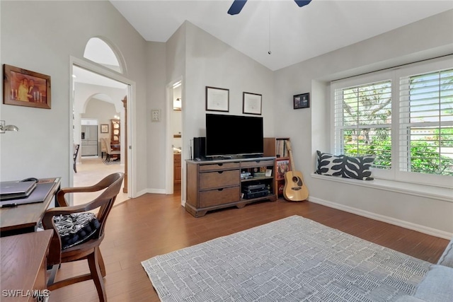 living room featuring baseboards, arched walkways, a ceiling fan, lofted ceiling, and wood finished floors