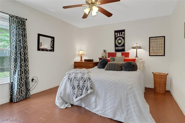 bedroom with ceiling fan, wood finished floors, and baseboards