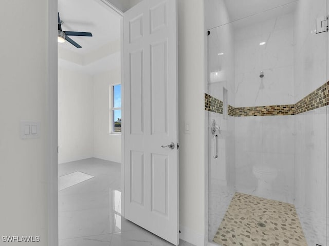 bathroom with toilet, marble finish floor, a stall shower, and a ceiling fan