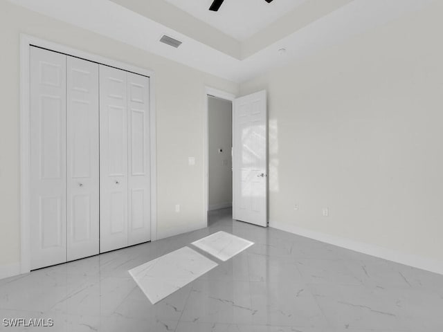 unfurnished bedroom featuring visible vents, marble finish floor, baseboards, and a tray ceiling