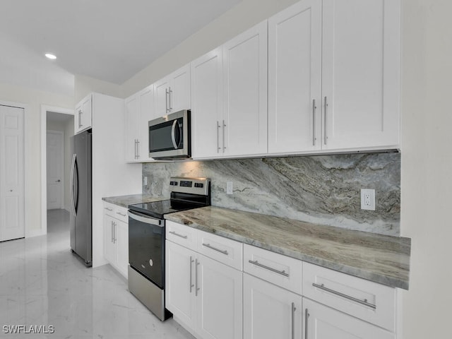 kitchen featuring marble finish floor, light stone counters, tasteful backsplash, white cabinetry, and appliances with stainless steel finishes