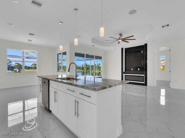 kitchen featuring visible vents, dishwasher, dark stone countertops, marble finish floor, and a sink