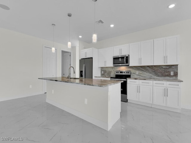 kitchen featuring marble finish floor, a sink, tasteful backsplash, stainless steel appliances, and stone counters