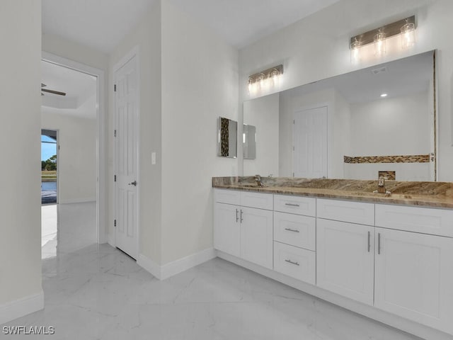 bathroom with double vanity, marble finish floor, baseboards, and a sink