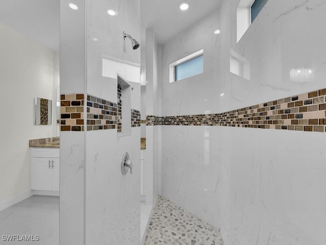 bathroom featuring vanity and a marble finish shower