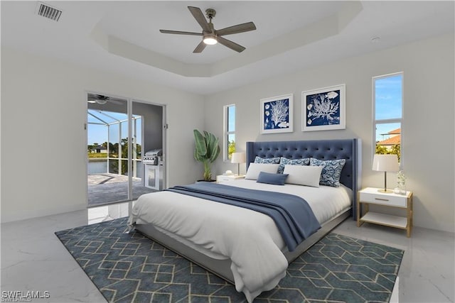 bedroom featuring a tray ceiling, access to exterior, and marble finish floor