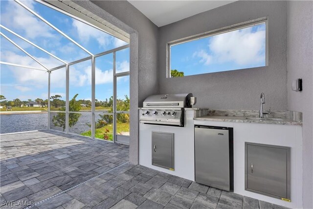 view of patio / terrace featuring glass enclosure, area for grilling, a sink, and a grill