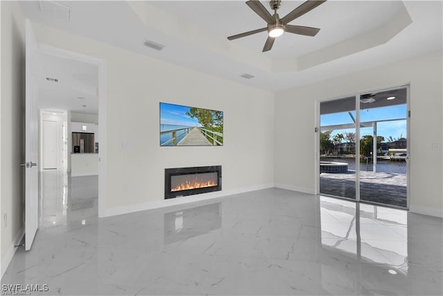 unfurnished living room featuring a glass covered fireplace, marble finish floor, a raised ceiling, and visible vents