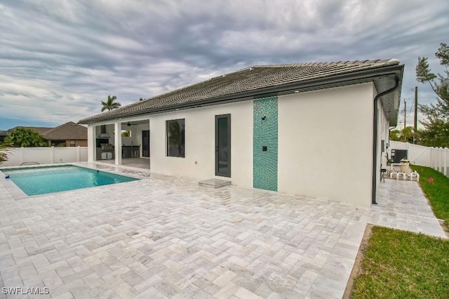 rear view of house with ceiling fan, a fenced backyard, a patio, and stucco siding