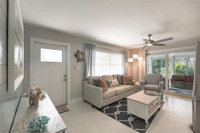 living area with ceiling fan and baseboards