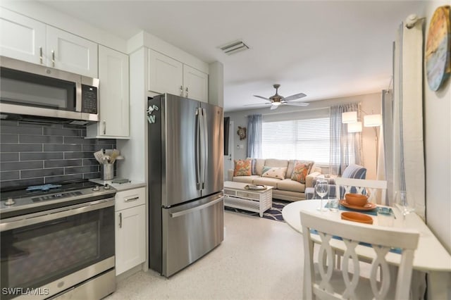 kitchen featuring a ceiling fan, stainless steel appliances, light countertops, white cabinetry, and backsplash